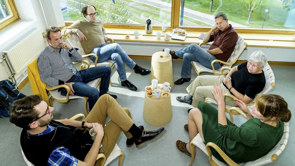 Six scientists sit around a table and talk. Photo.